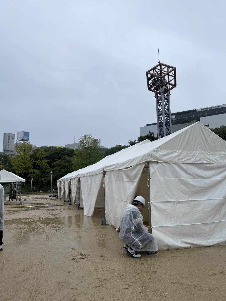 雨でぬかるんだ屋外イベント会場でのテント設営作業