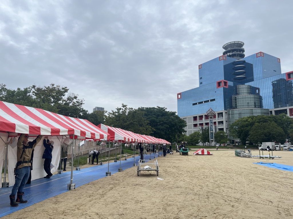 養生マットを敷いた屋外イベント会場の通路とテント列